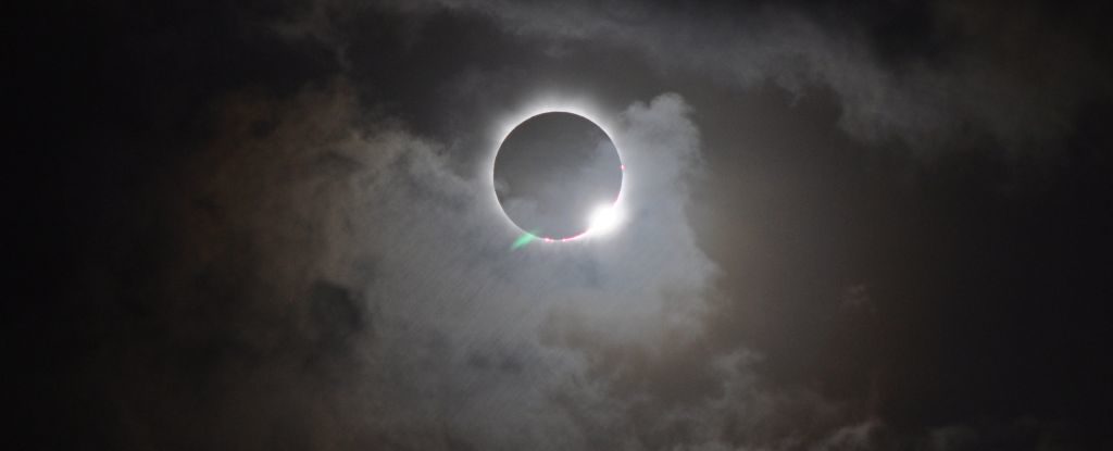 the dramatic ring of light of a total solar eclipse, with clouds drifing across the moon and sun