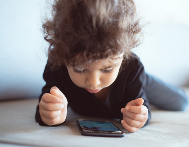 A child looking down at a smart phone