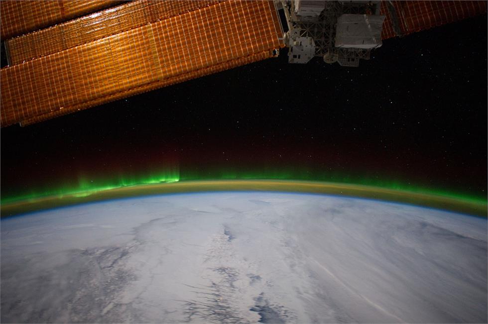     Aurora boreal bajo los paneles solares de la ISS