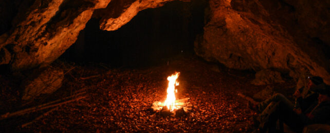 Fire burning inside a dark cave with a low roof.