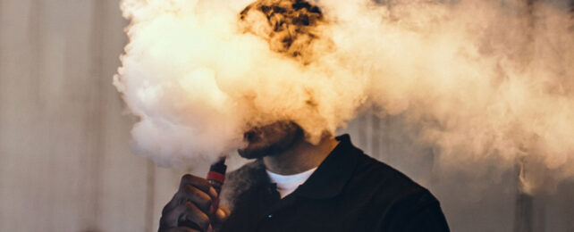 Vaping man with head in the cloud of vape smoke