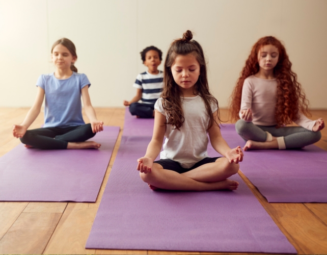 Children crossing their legs on a yoga mat