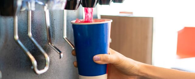 hand pours soft drink into cup