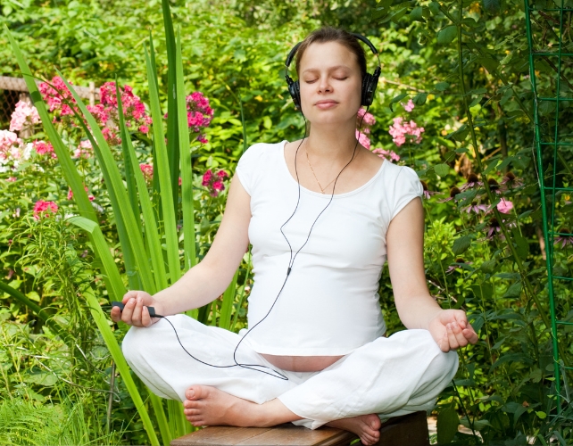 Feminine person wearing white clothes sitting in the garden and meditating