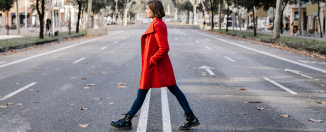 woman in red coat walking across a street