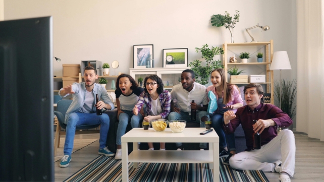 A group of adults on a couch watching TV