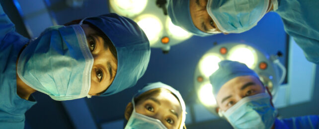 surgeons looking down at awake patient