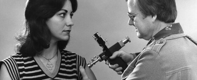 Women being vaccinated with a et injector by a man