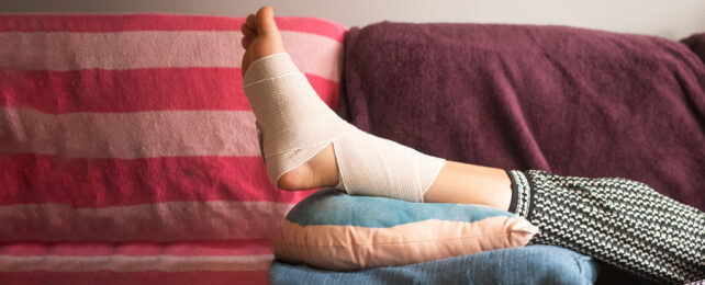 Bandaged leg up on several cushions on couch