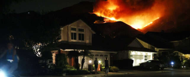 Fire blazing hot behind a house in California