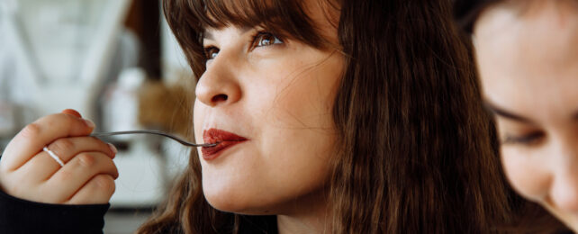 close up of women holding fork in mouth