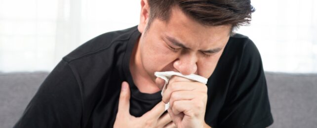 A man coughing into a napkin in his hand