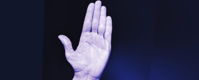 An open palm in a purple tinge against a black background