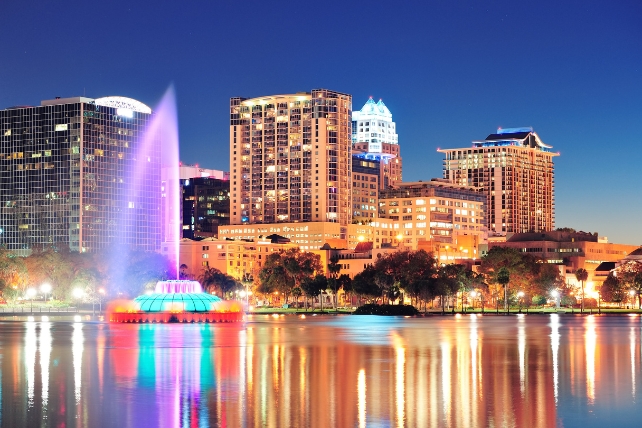 A city skyline at night with lights reflecting in a river in the foreground