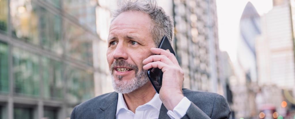 A man wearing a suit looking concerned while talking on a mobile phone