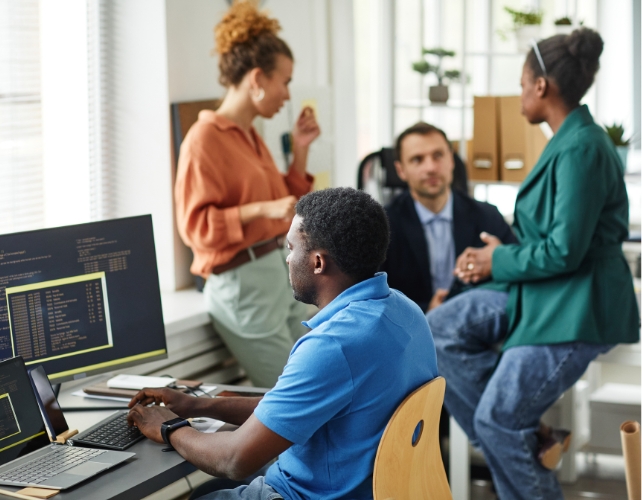 People in an office talking and on a computer