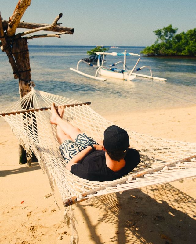 Man lying on a hammock in the sun on a beach