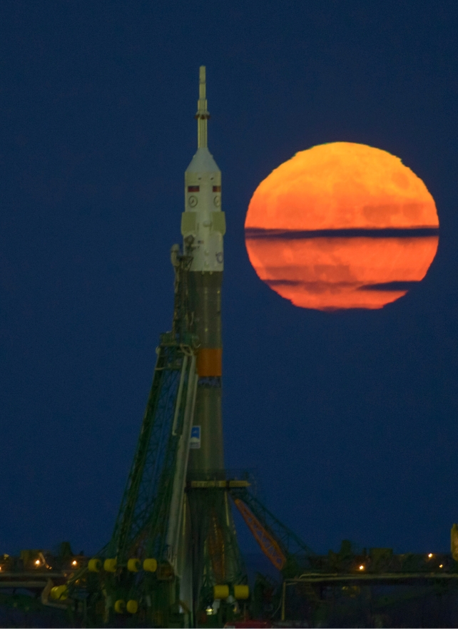 A bright orange moon behind a rocket 