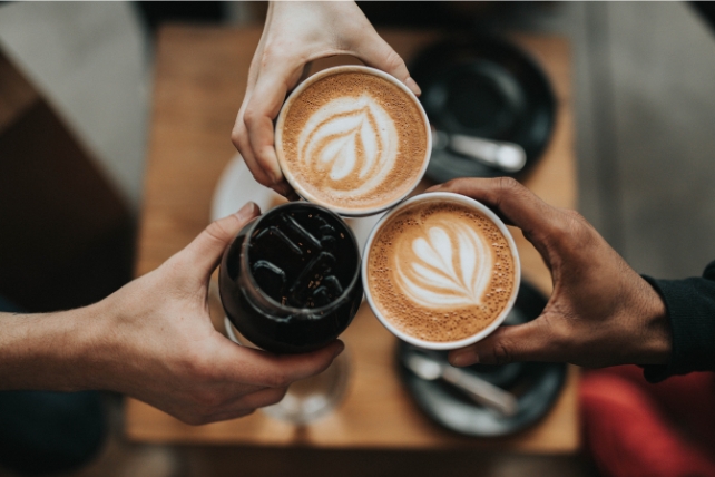 Three coffees being held by hands