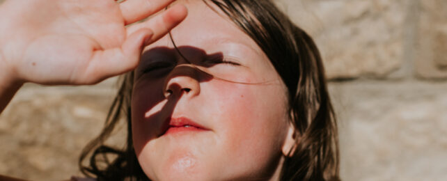 girl shielding her eyes from the glare of the sun