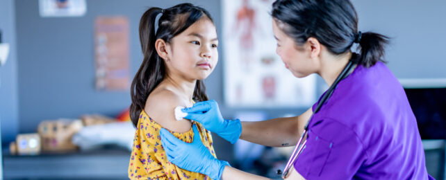 doctor holding cotton ball on girl's arm