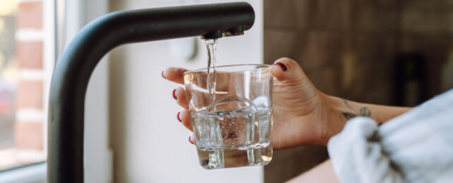 a person pouring water from a tap