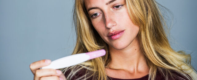 woman looking at a pregnancy test