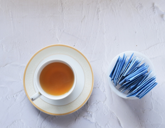 Aerial view of a cup of tea next to sachets of sweetener