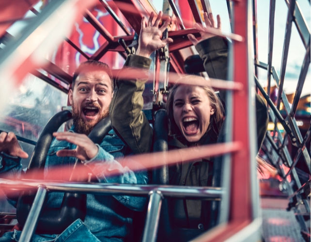 Two people on a rollercoaster, looking happy and/or scared