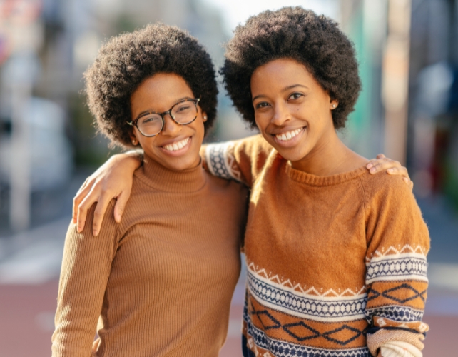 Twin sisters smiling with arms around each other