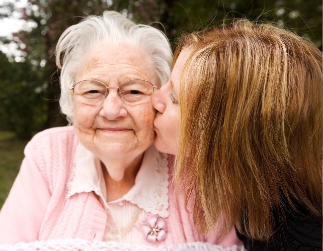 A young person kissing an older lady on the cheek