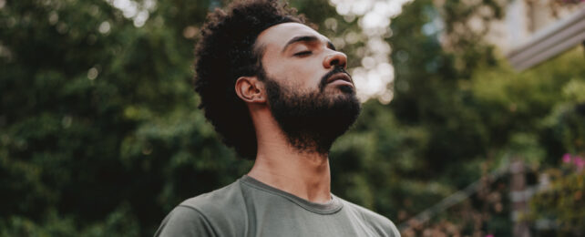 man with eyes closed, sniffing the air