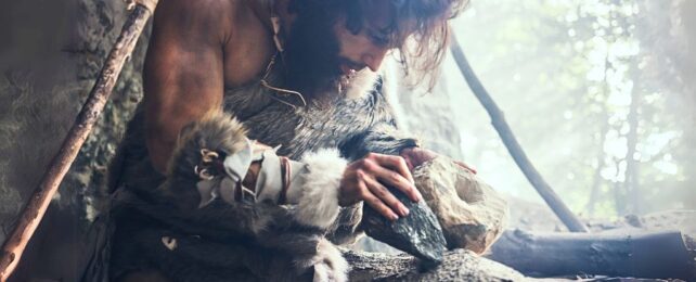 Man dressed as a cave man working with stone tools