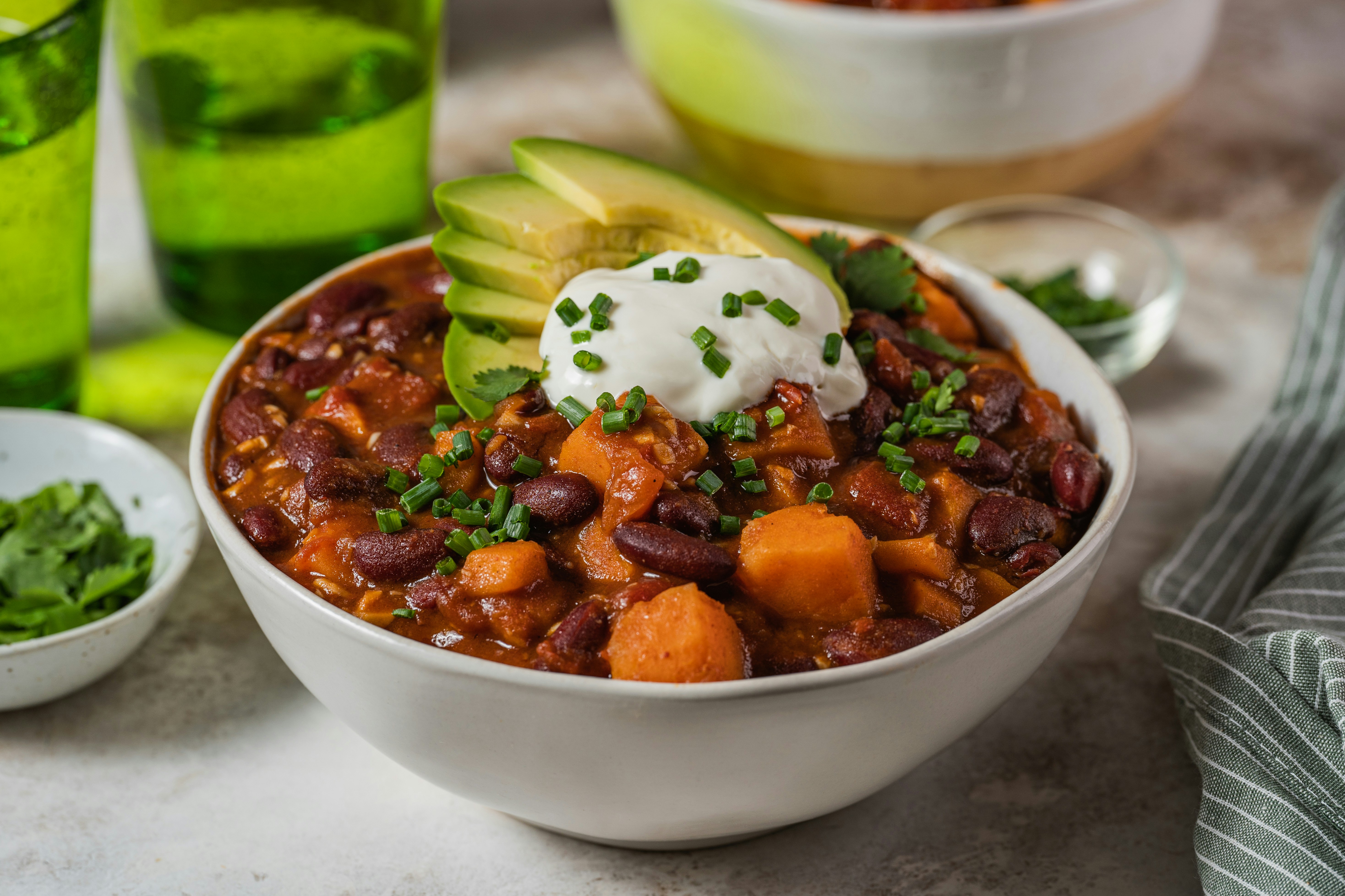 Bean and sweet potato stew with avocado in a white bowl