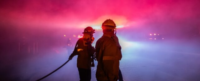 Two firefighters in colorful haze