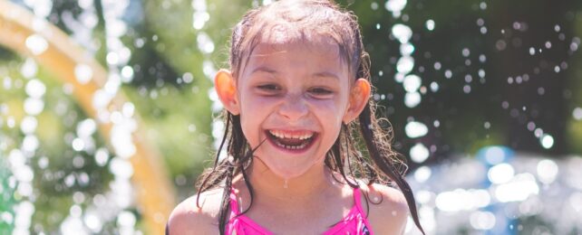 A smiling child with water splashing around them