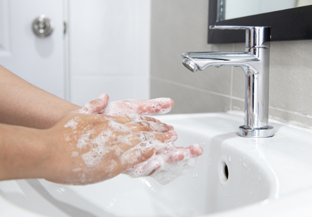 Soapy hands next to a tap and basin