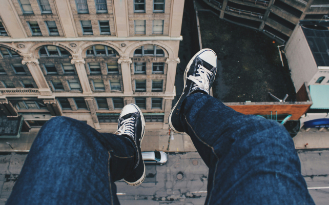 feet hanging over the edge of a building