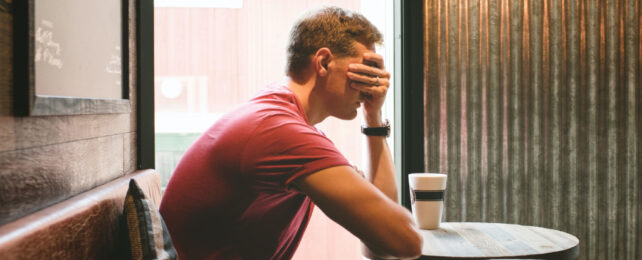 man sitting at a table holding his hand over his eyes