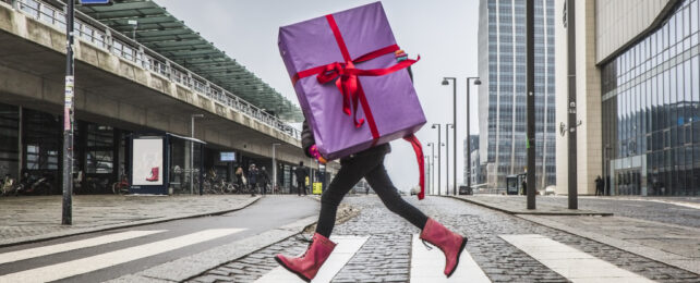 person carrying a big gift across the street