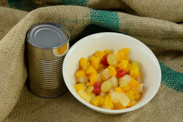 Canned fruit cocktail poured out into a white bowl