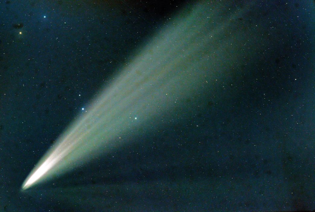 Comet flaring green against dark blue night sky