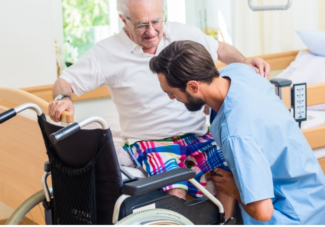 Nurse helps senior man into wheelchair