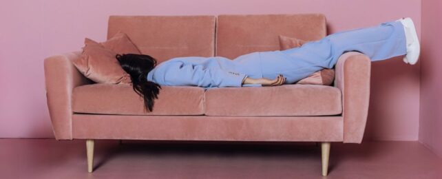 Woman lying face down on a pink couch