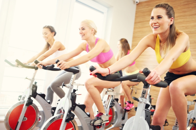 Women on spin bikes smiling