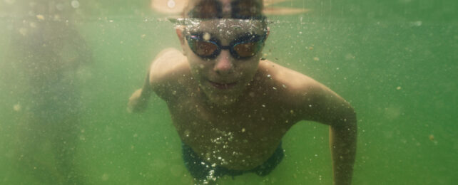 teen swimming in water hole underwater