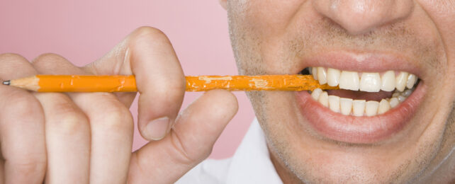 man chewing on a wooden pencil