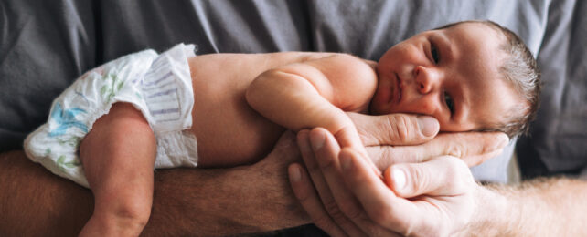 newborn baby being held by father